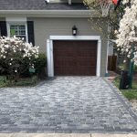 Brick paver driveway in front of a Chicago-area home with a wood garage door and blooming magnolia