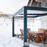 Hard top pergola protecting patio from snow