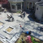 Crew installing a paver patio with cutting equipment and stacked pavers behind a brick home in the Chicago suburbs
